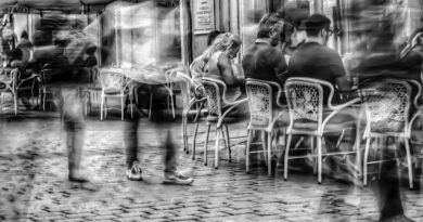 grayscale photography of people sitting on bistro chairs