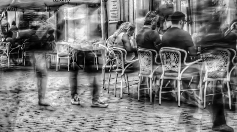 grayscale photography of people sitting on bistro chairs